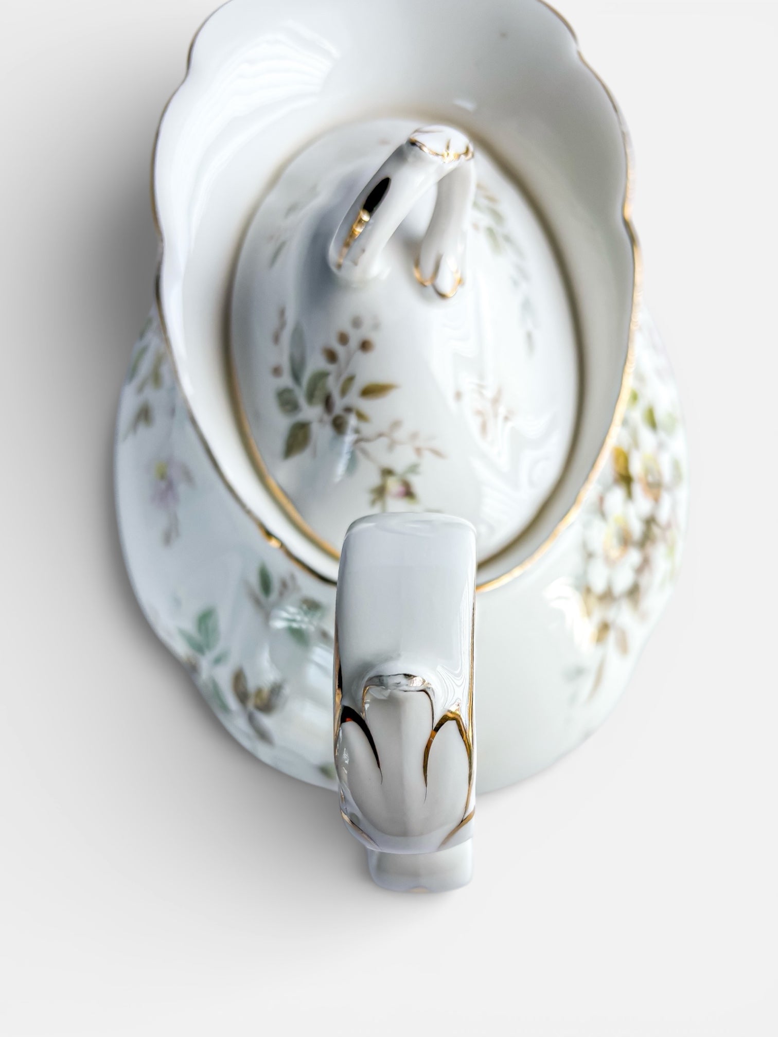 Vintage porcelain covered bowl with delicate floral patterns and gold trim, top view