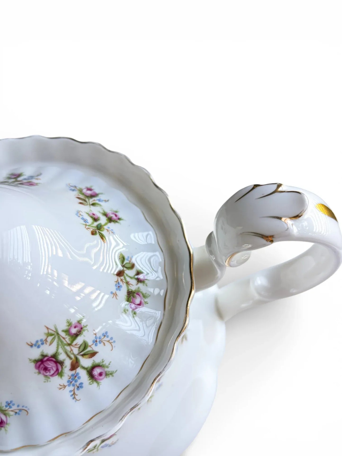Detailed view of the teapot handle showing the elegant scrollwork and minor vintage rubbing to the 22-carat gold trim.
