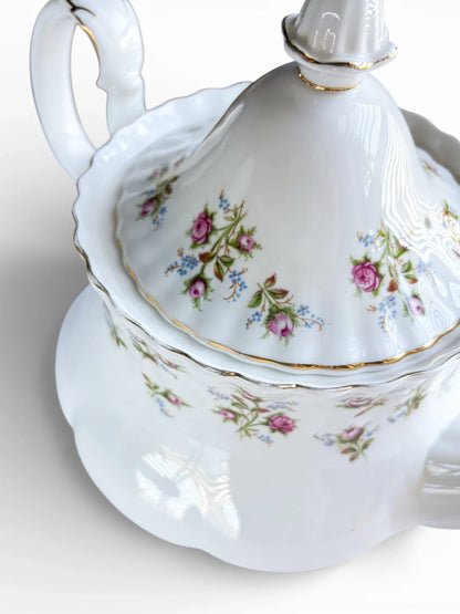 Close-up of the teapot's side showing the floral decoration, steam vent, and gold-trimmed finial.