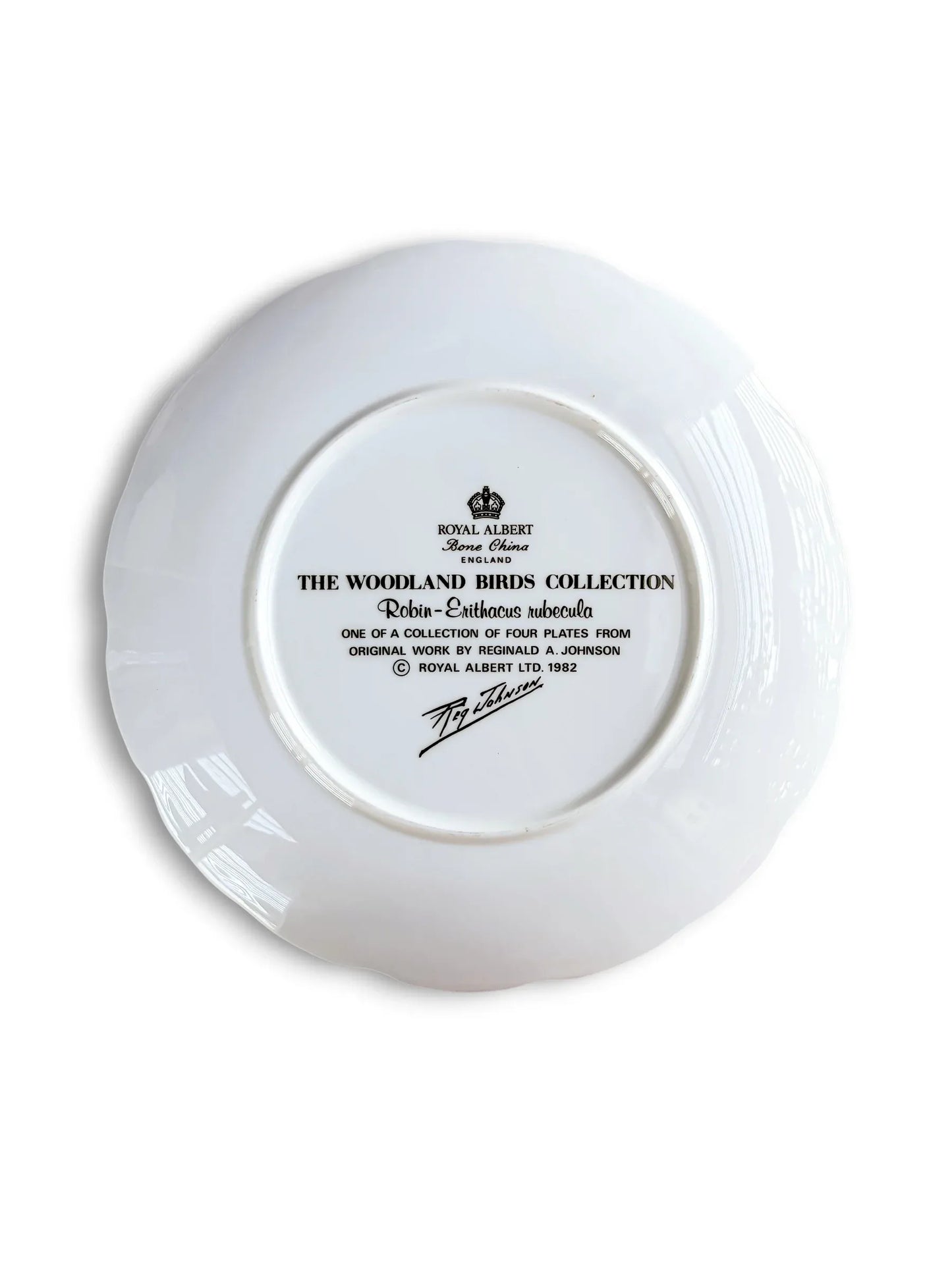 The backstamp of a vintage Royal Albert fine bone china plate showing the black crown logo, "Made in England," and text identifying it as part of "The Woodland Birds Collection" featuring the Robin (Erithacus rubecula), dated 1982 with the artist’s signature.