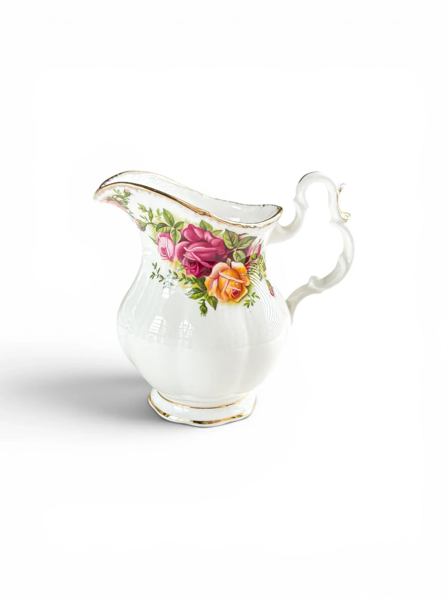 Side profile of a vintage Royal Albert Old Country Roses creamer jug in the Avon shape, highlighting its tapered vertical fluting and ornate gilded scroll handle.