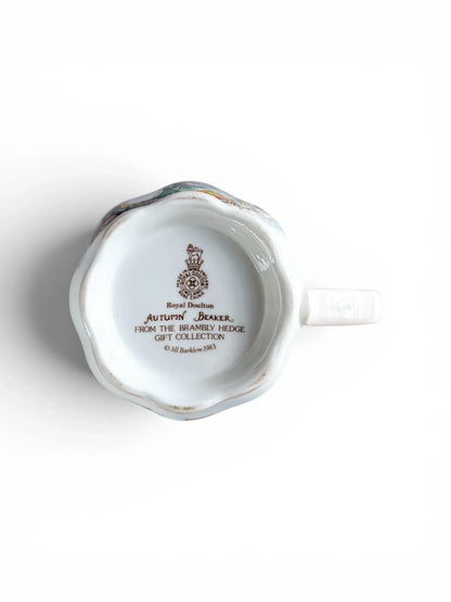 Close-up of the underside of the Royal Doulton Autumn beaker, showing the official brown backstamp with the Lion and Crown crest, "Made in England," and the 1983 copyright date for Jill Barklem and the Brambly Hedge Gift Collection.