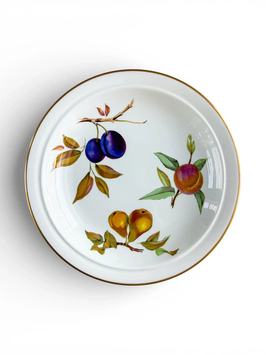 A vintage Royal Worcester Evesham Gold rimmed soup bowl with a clean white rim and detailed fruit studies of a purple plum, a peach, and a pear in the central well.