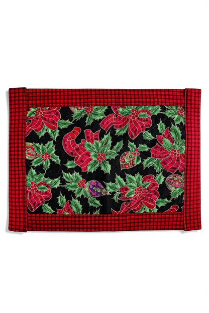 Christmas placemat with red plaid border and holly leaves, red ribbons, and ornaments on black background