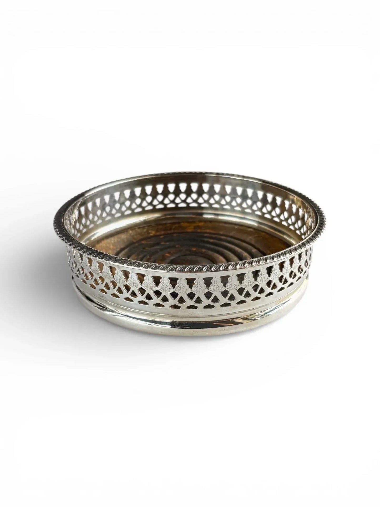 Angled view of a silver-plated vintage wine coaster displaying both the reticulated metal rim and the rich wooden interior.