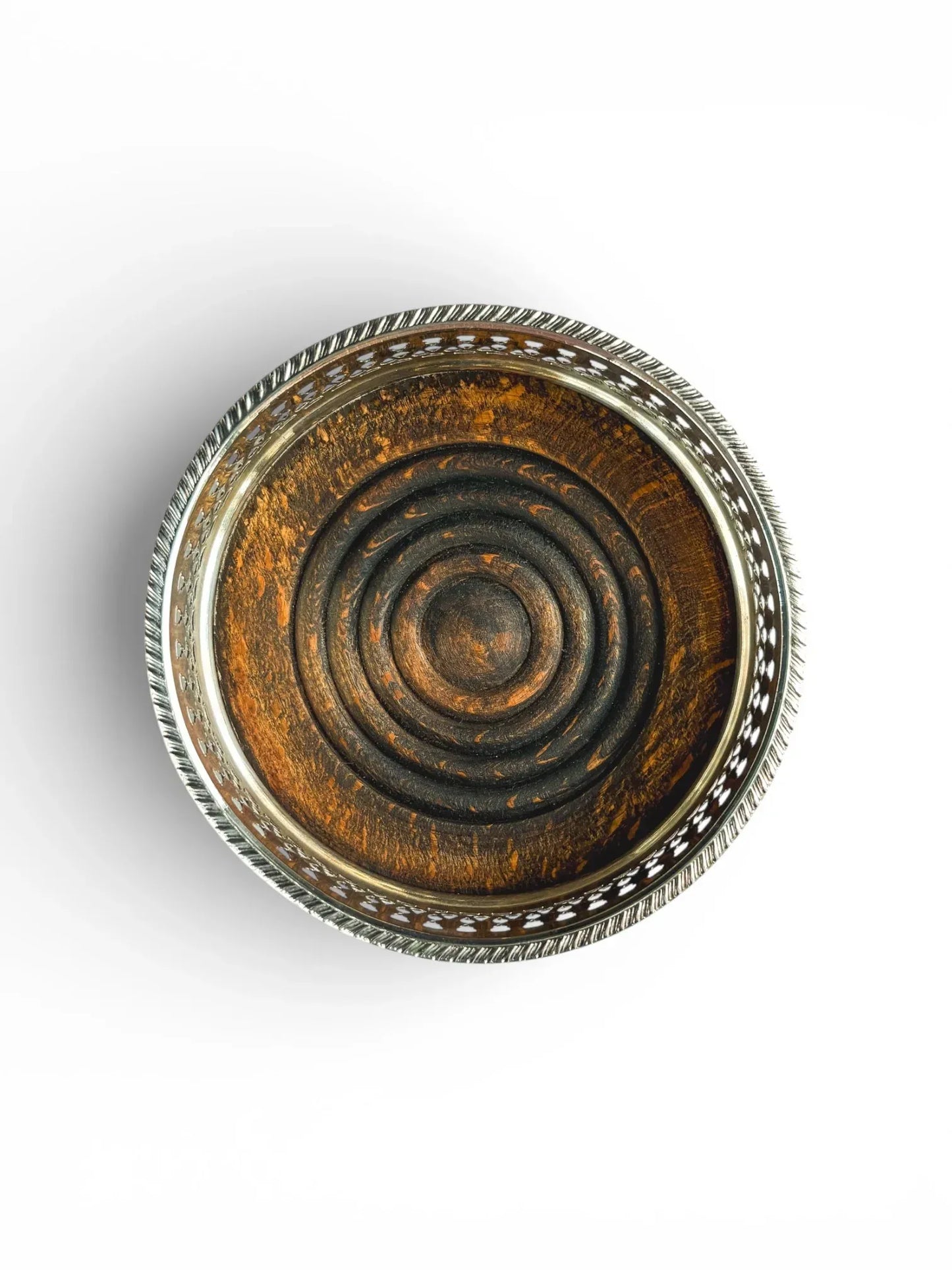 Top-down view inside a vintage wine coaster revealing a dark, turned wood base carved with concentric rings.