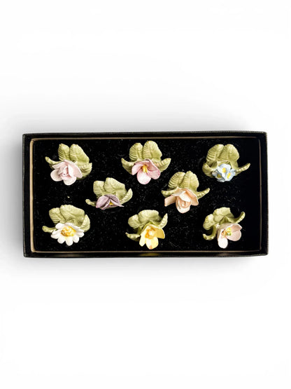 Flat lay view of 8 hand-modelled porcelain flower place card holders in a boxed set, made in England.
