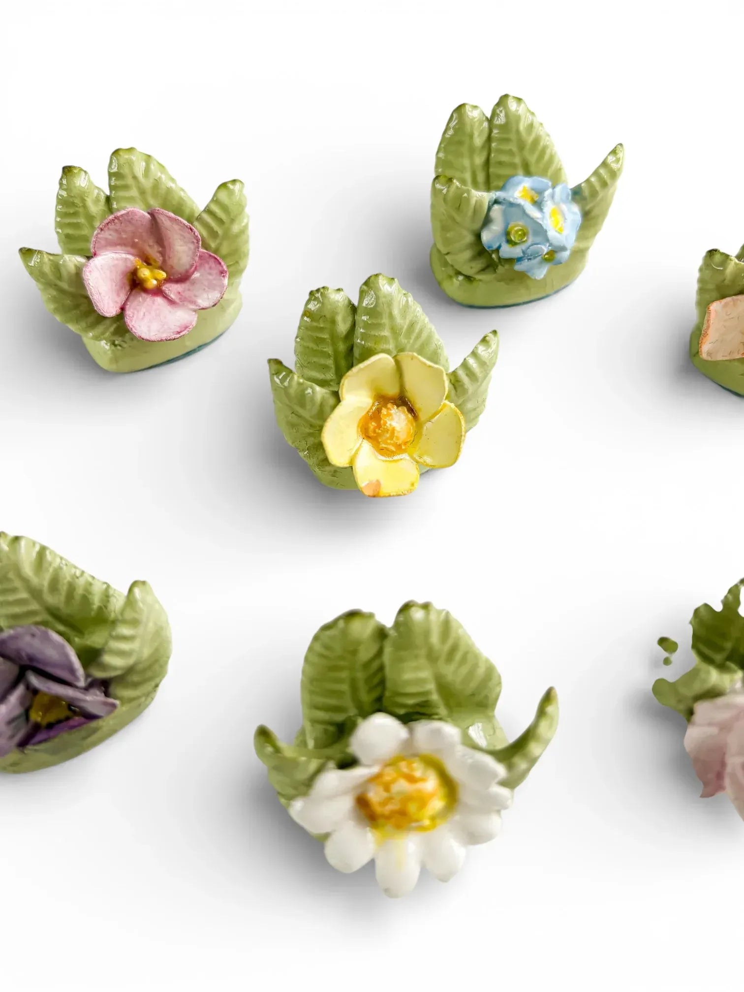 Macro detail of hand-painted porcelain petals and green leaves on vintage English bone china table accessories.