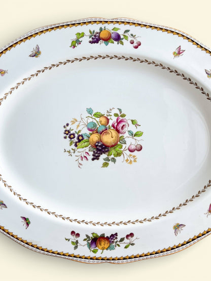 Vintage porcelain serving platter with colorful fruit and floral patterns, decorative butterflies, and gold trim