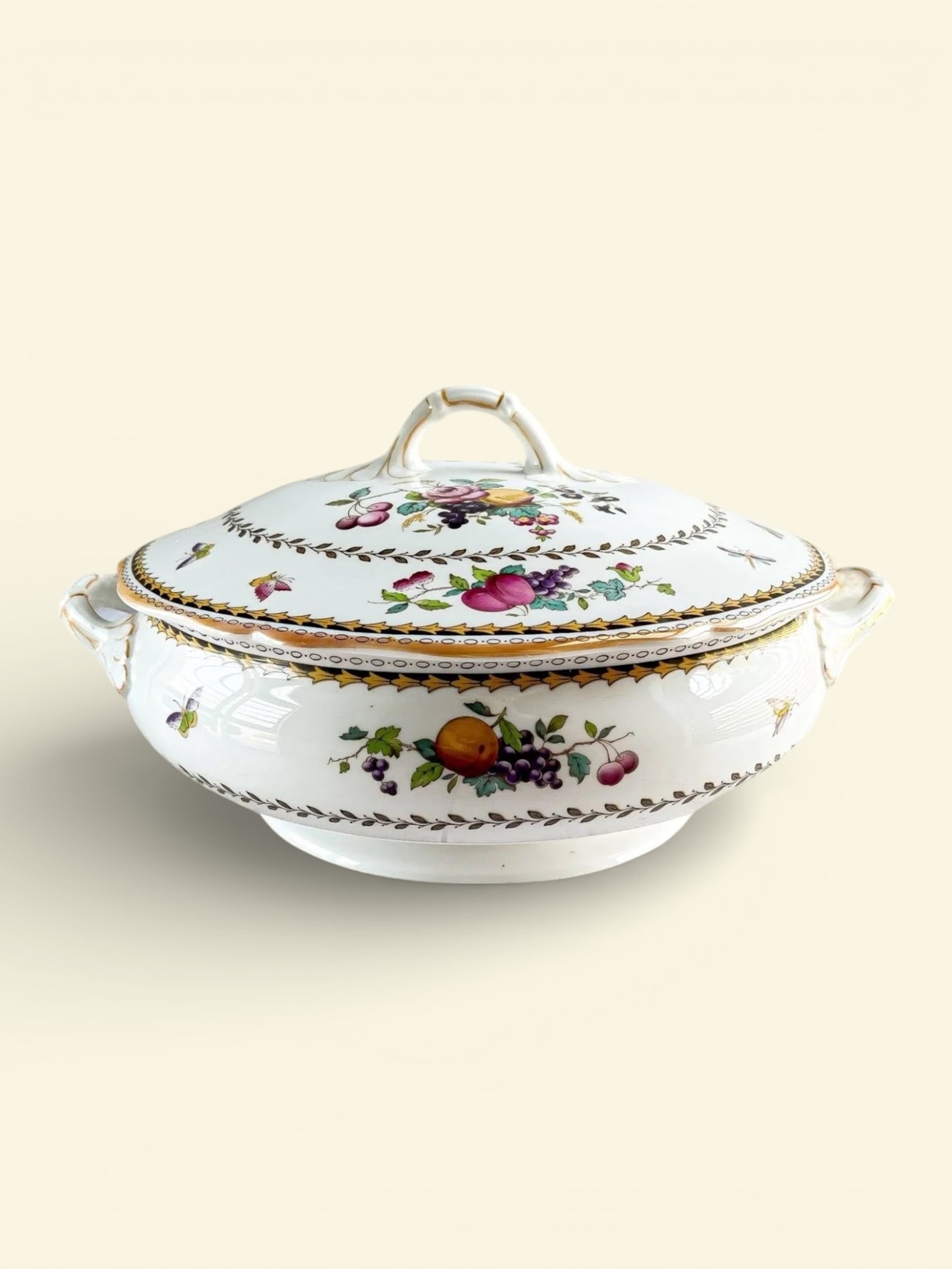 Vintage porcelain covered serving dish with colorful fruit and floral patterns on cream background