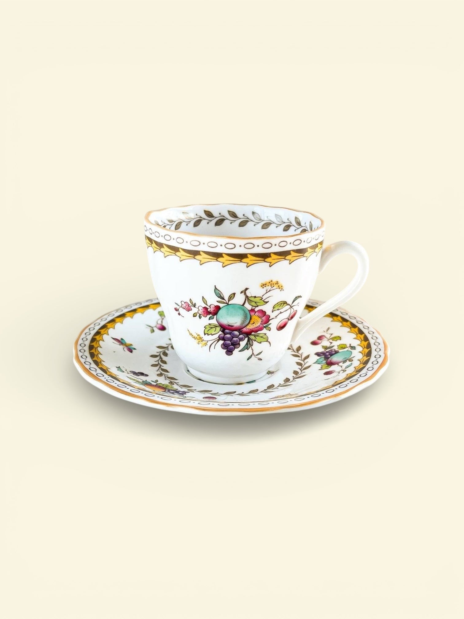 Vintage porcelain teacup and saucer set with floral and fruit motifs and gold trim