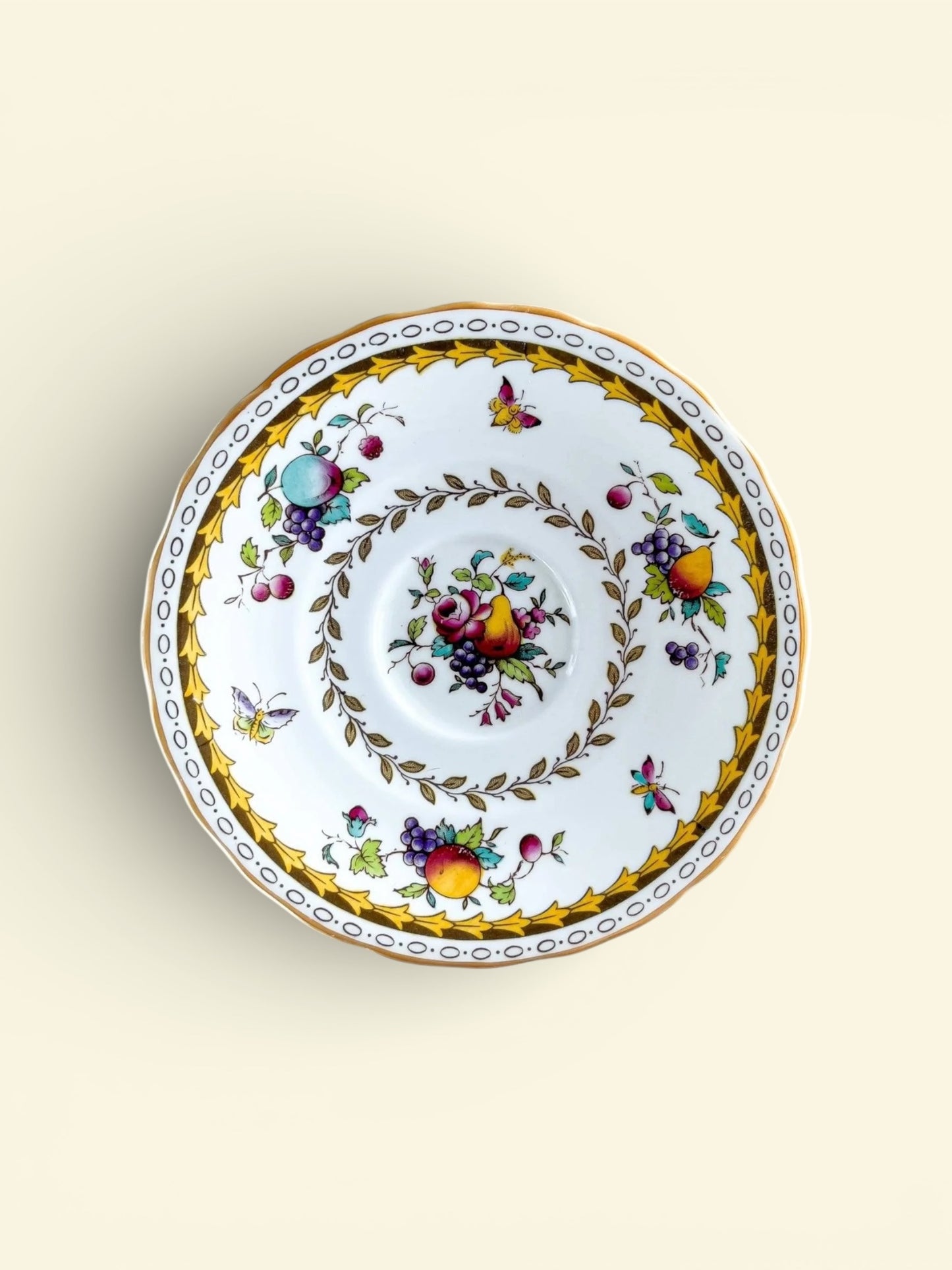 Vintage porcelain plate with gold leaf border and colorful fruit and butterfly designs