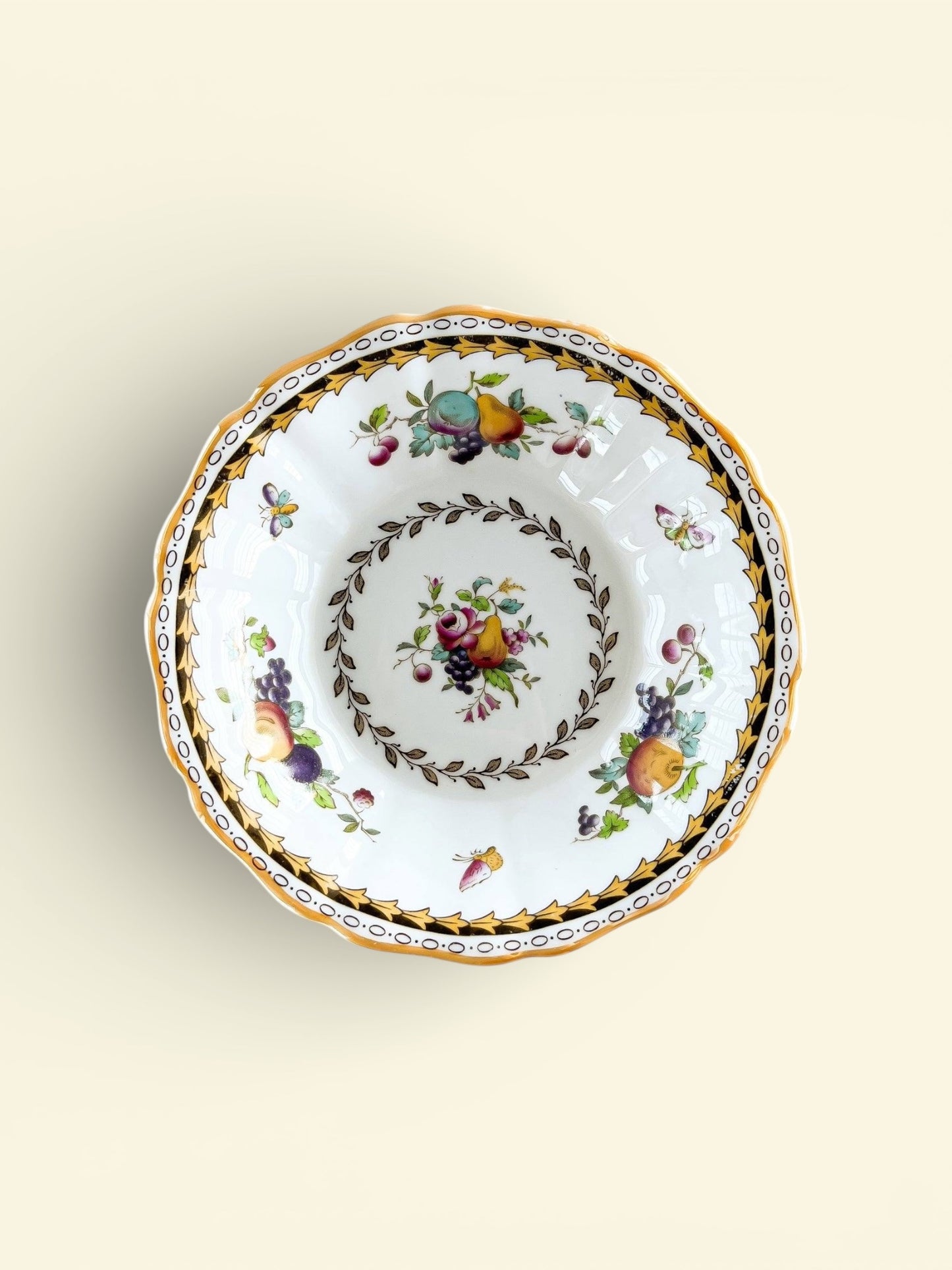 Vintage porcelain bowl with fruit and floral patterns, gold and black decorative border
