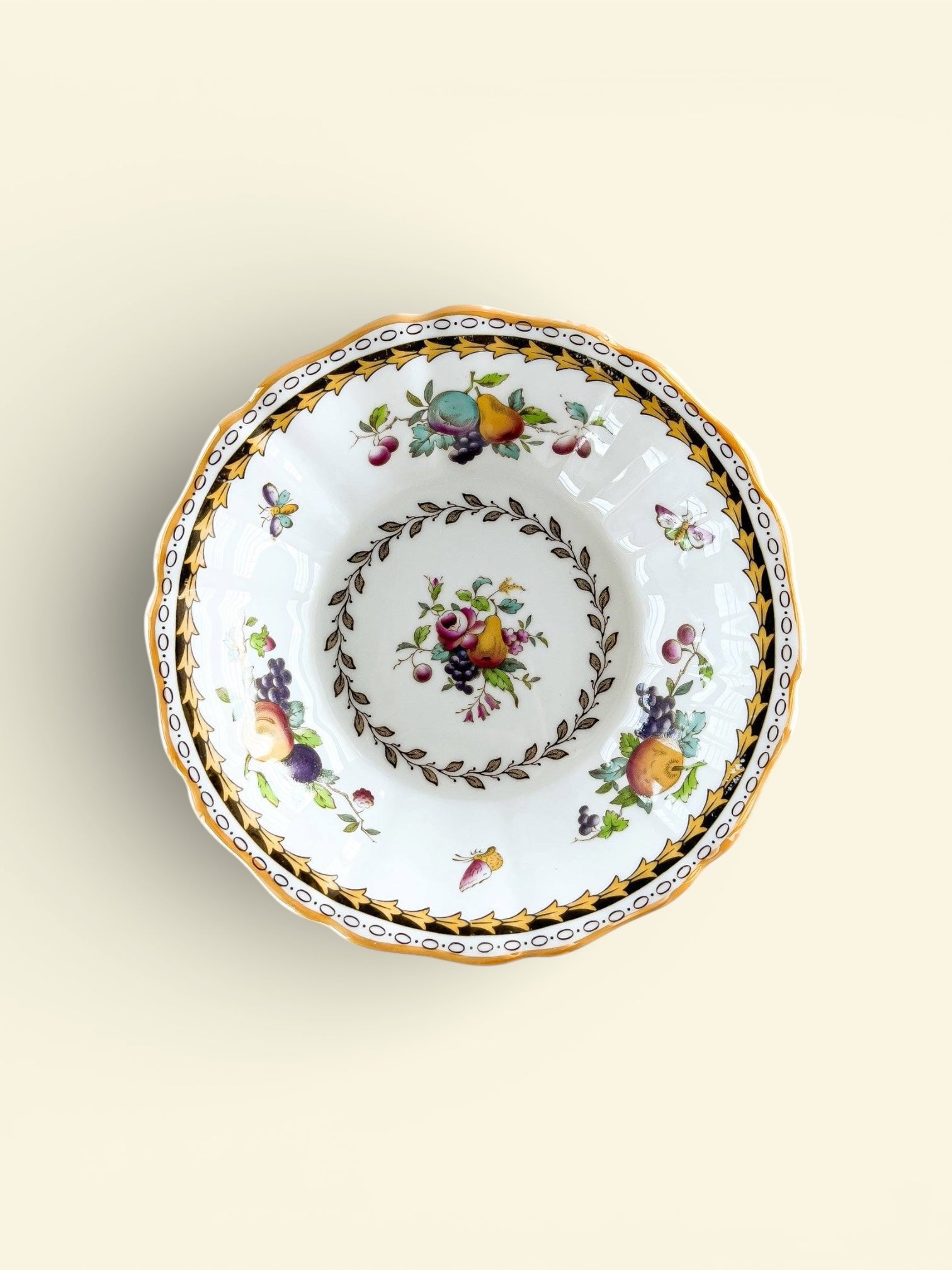 Vintage porcelain bowl with fruit and floral patterns, gold and black decorative border