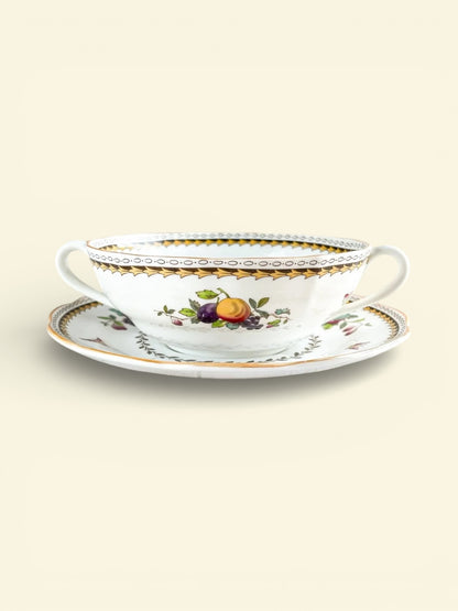 Vintage porcelain soup cup with two handles and matching saucer, decorated with gold trim and fruit motifs