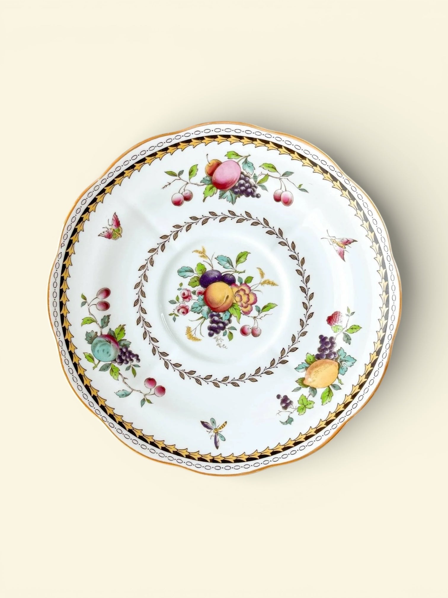 Vintage porcelain plate with colorful fruit and floral patterns, gold and black decorative trim