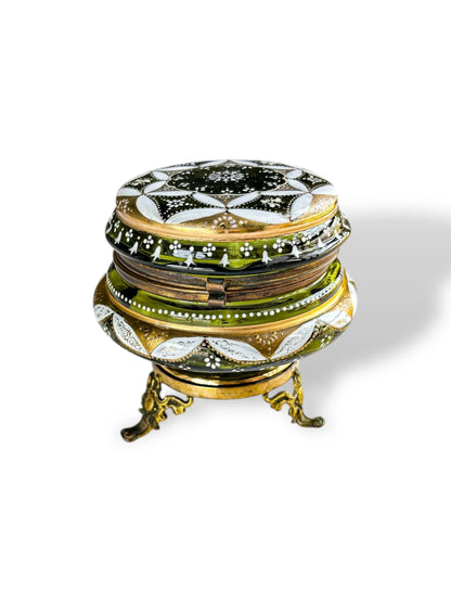 Green and gold vintage glass trinket box with ornate enamel design and brass legs