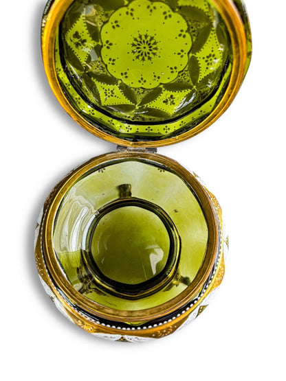 Vintage green glass trinket box with gold trim and decorative floral lid on white background
