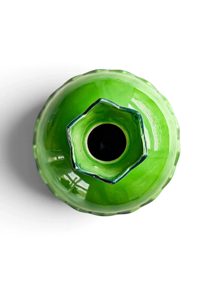 Overhead view of a vintage green ceramic pomegranate vase, looking into the pointed sepal crown and the open mouth.
