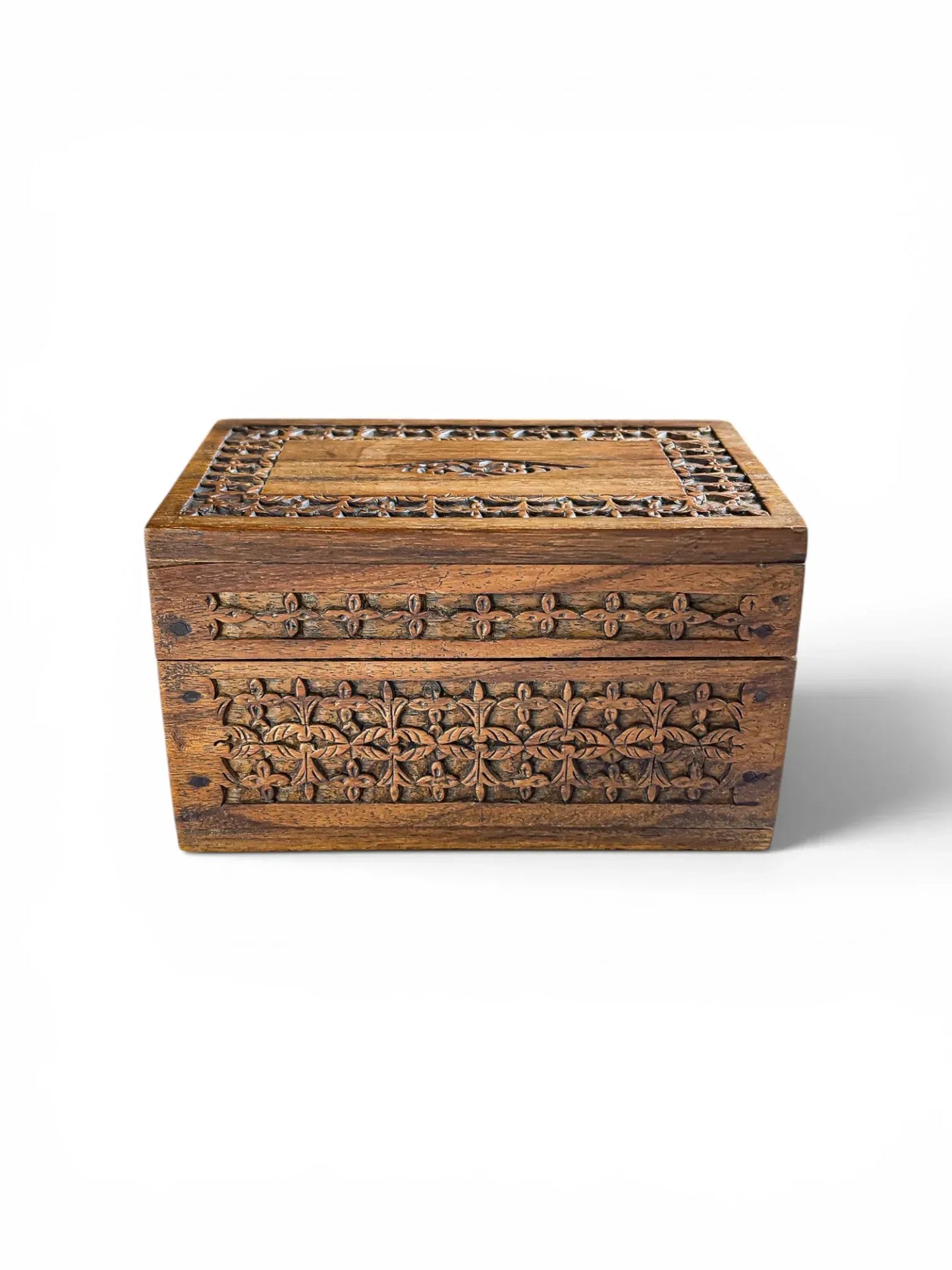 Front view of a rectangular, vintage hand-carved hardwood trinket box against a solid white background, showcasing a deep geometric floral frieze carved into the rich, grained wood.
