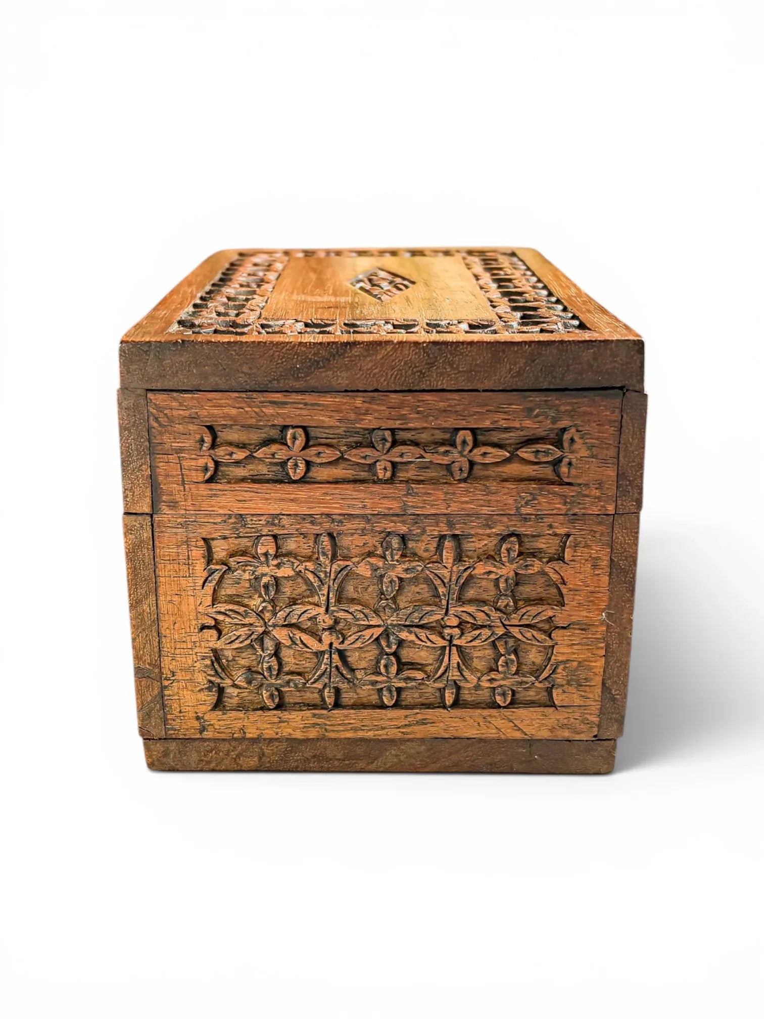 Side profile view of a mid-century hand-carved wooden trinket box against a white background, displaying the detailed relief carving and rich natural grain patterns of the hardwood.