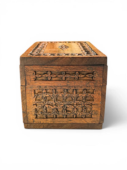 Side profile view of a mid-century hand-carved wooden trinket box against a white background, displaying the detailed relief carving and rich natural grain patterns of the hardwood.