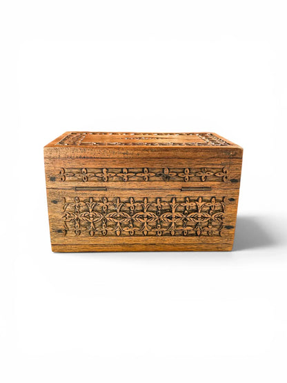 Rear view of a vintage hand-carved wooden box against a clean white background, showing the flush-mounted rectangular brass hinges and traditional joinery.