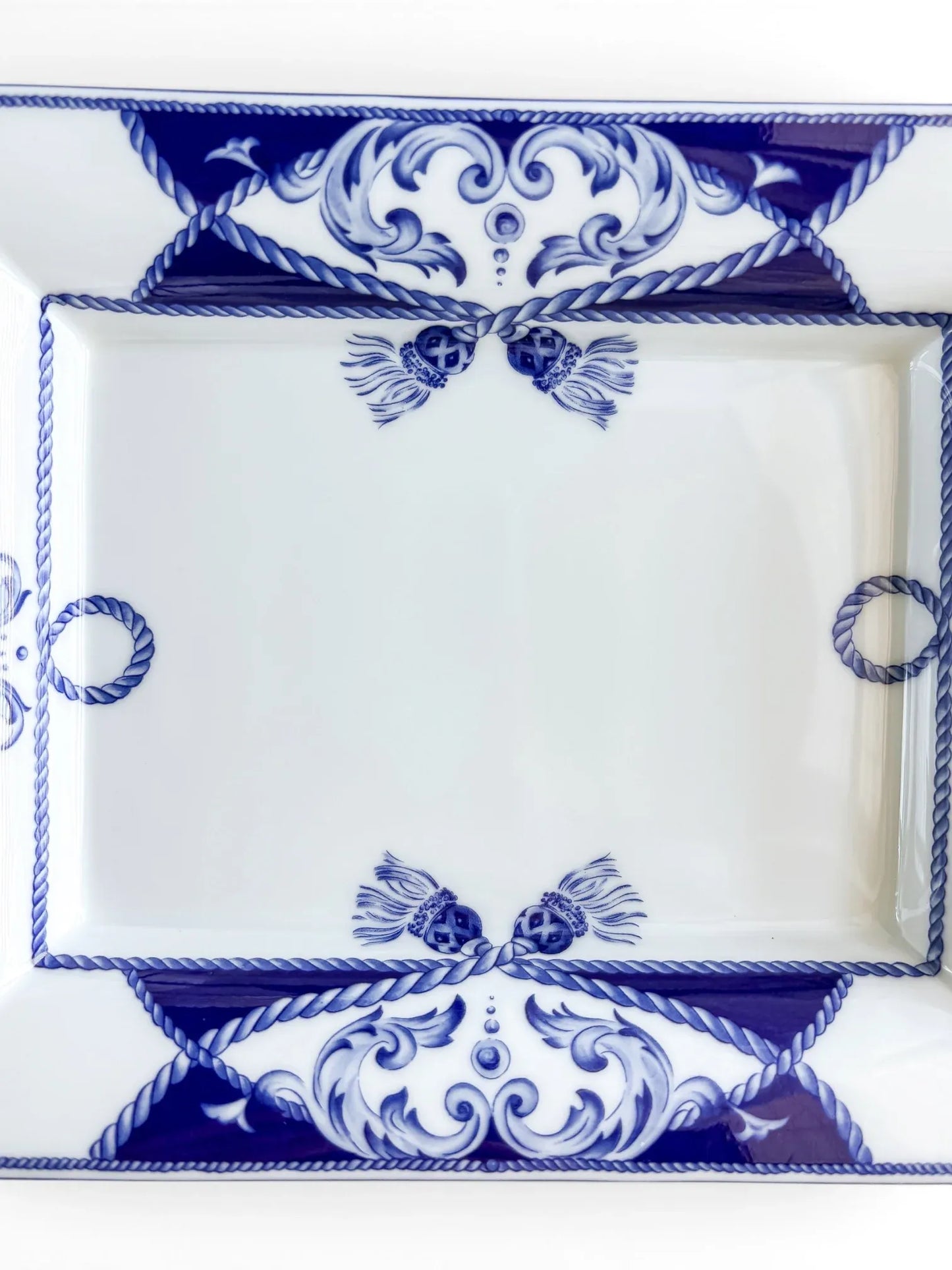 Close-up of the Vista Alegre Villa dish well, with paired cobalt tassels, rope rings and blue scrollwork on glossy white porcelain.