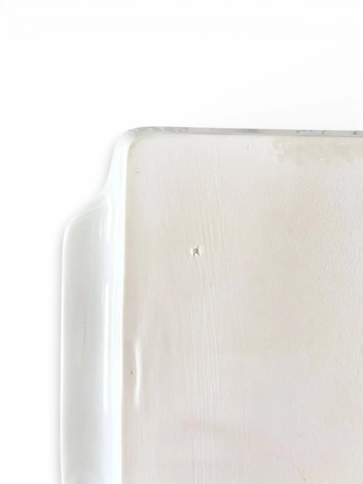 Close-up of a white porcelain rectangular tray corner with smooth glazed finish