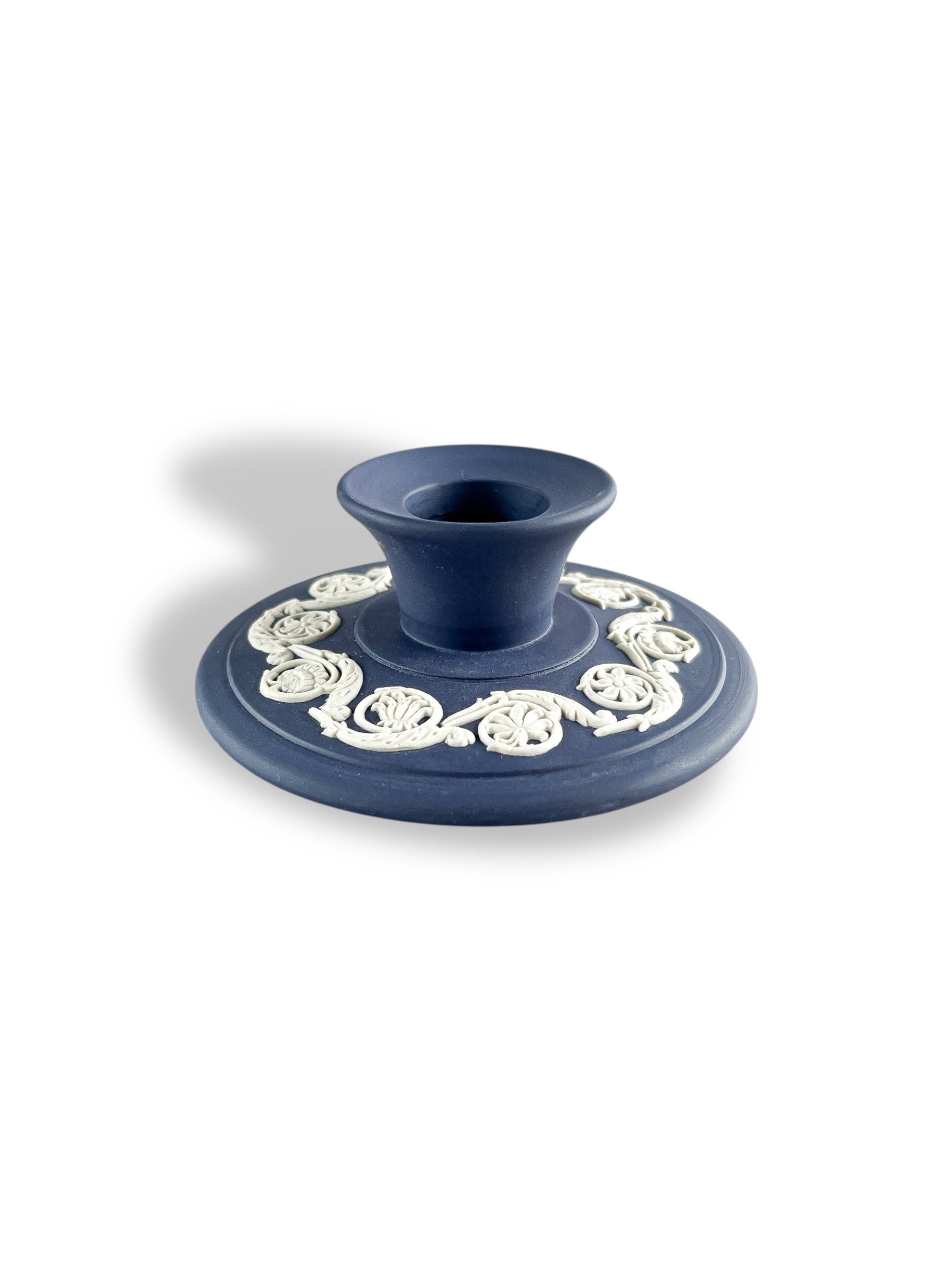 blue porcelain candle holder with white intricate floral detailing on round base