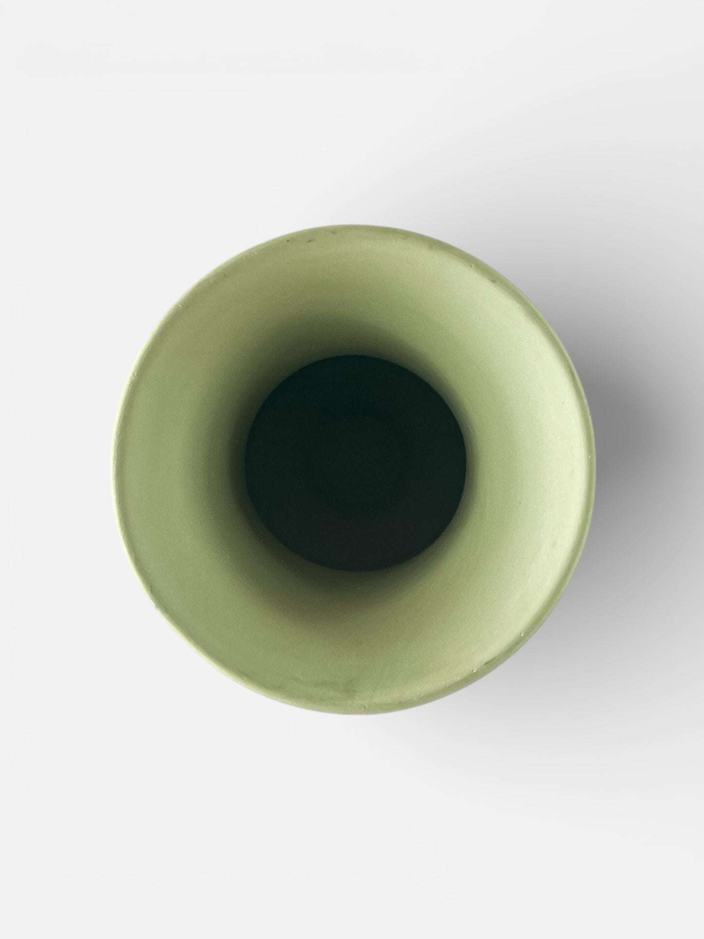 Top view of a green ceramic vase with smooth matte finish on a white background