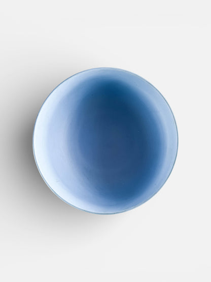 Top view of a simple blue ceramic bowl with smooth texture on white background