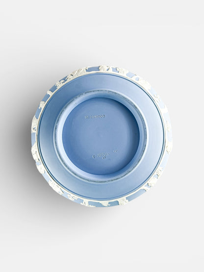 Top view of a blue Wedgwood porcelain plate with white relief decorations around the edge, marked Made in England