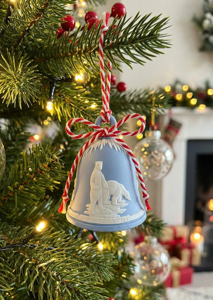 Blue ceramic bell ornament with polar bears and red-white twine on Christmas tree with lights