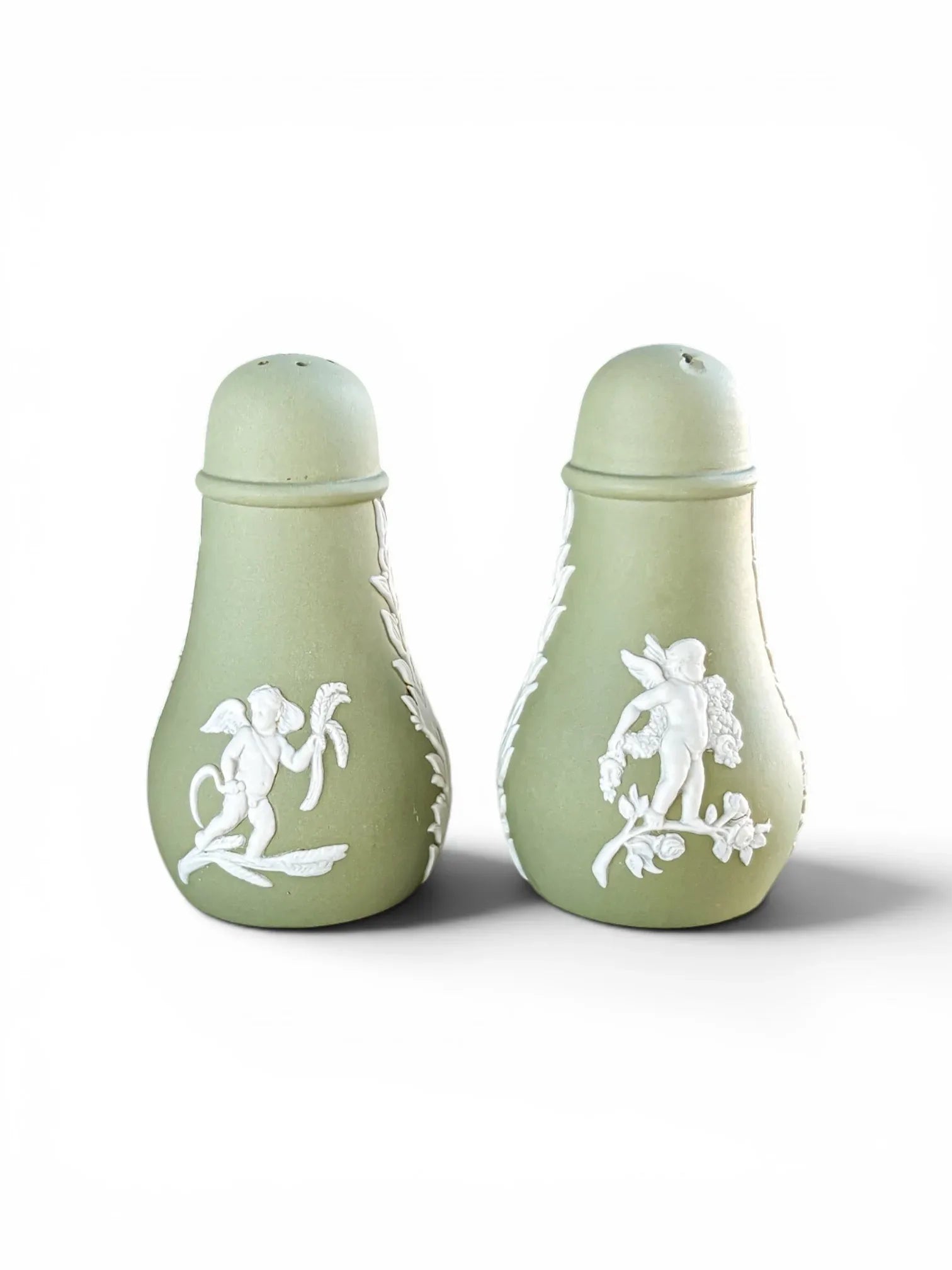 Alternate view of the vintage Wedgwood sage green Jasperware salt and pepper shakers, showcasing different classical white cherub motifs on the matte stoneware bodies.