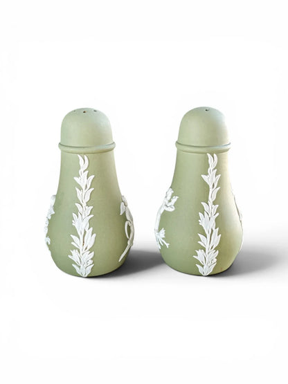 Profile view of the vintage Wedgwood sage green Jasperware salt and pepper shakers, highlighting the intricate white sprigged acanthus leaf vertical border columns.
