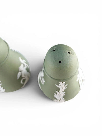 A close-up, high-angle view focusing on the domed top of the three-hole vintage Wedgwood sage green Jasperware shaker, detailing a small historic flea bite chips near the upper piercings.