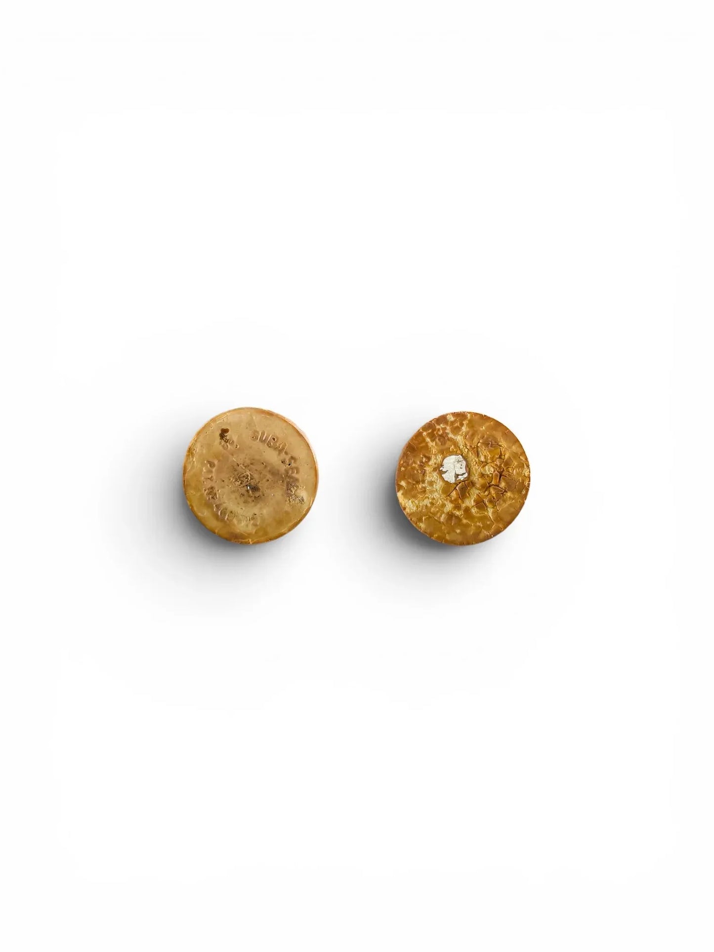 Flat lay view of the undersides of two vintage Suba-Seal rubber stoppers for the shakers, showing authentic age-related texture, crackling, and partial branding marks on the aged brown rubber.