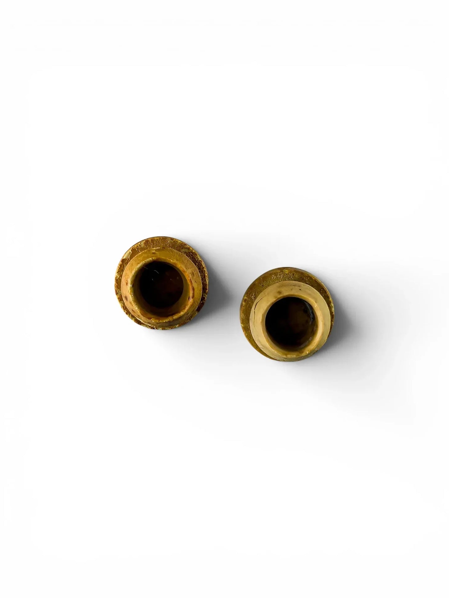 Top-down view into the hollow centers of the two aged rubber shakers stoppers, isolated against a crisp white background.