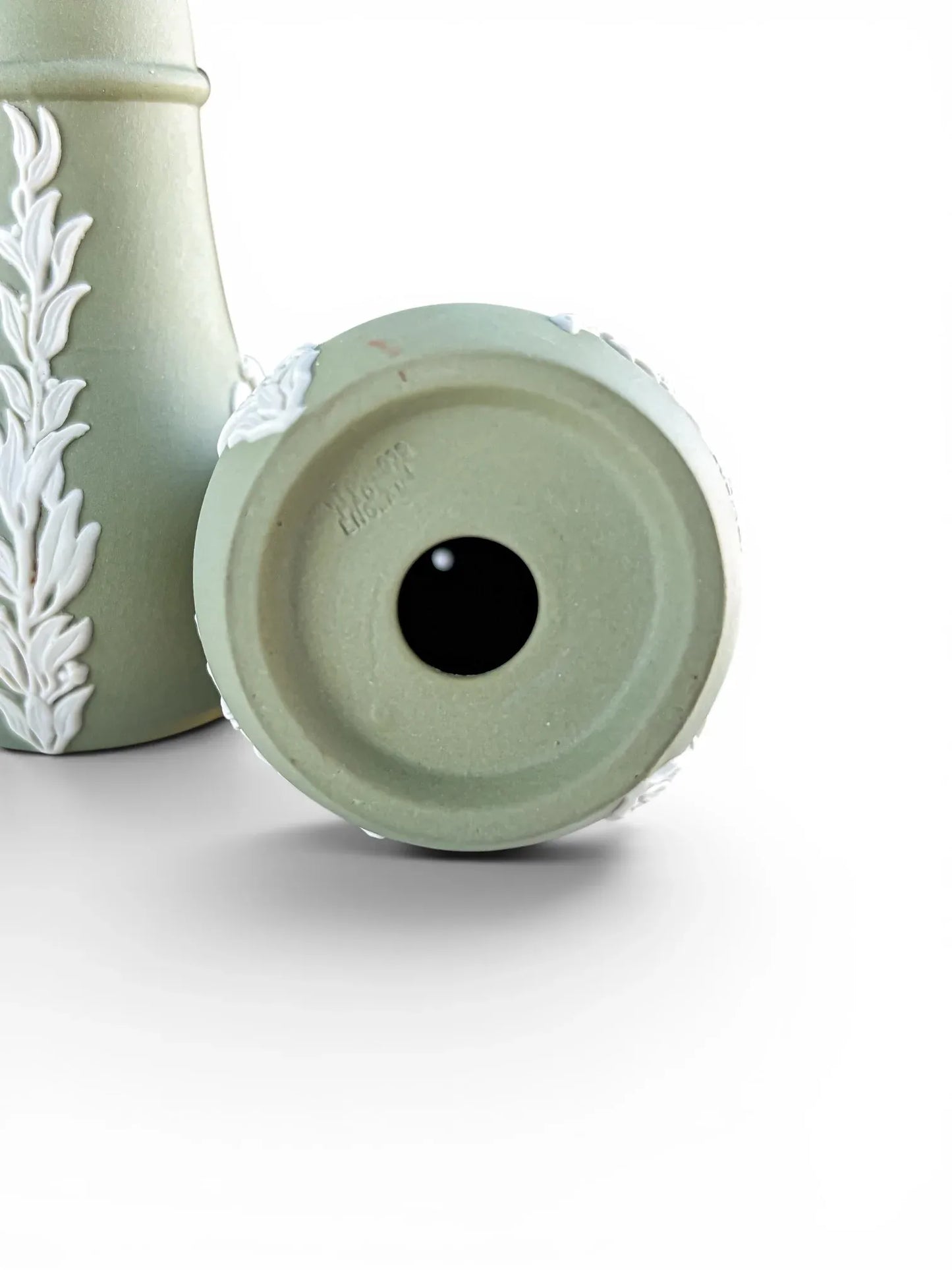 Close-up view of the underside base of a sage green Wedgwood Jasperware shaker, showcasing the authentic, crisp impressed "WEDGWOOD ENGLAND" maker's mark stamped into the unglazed stoneware clay.