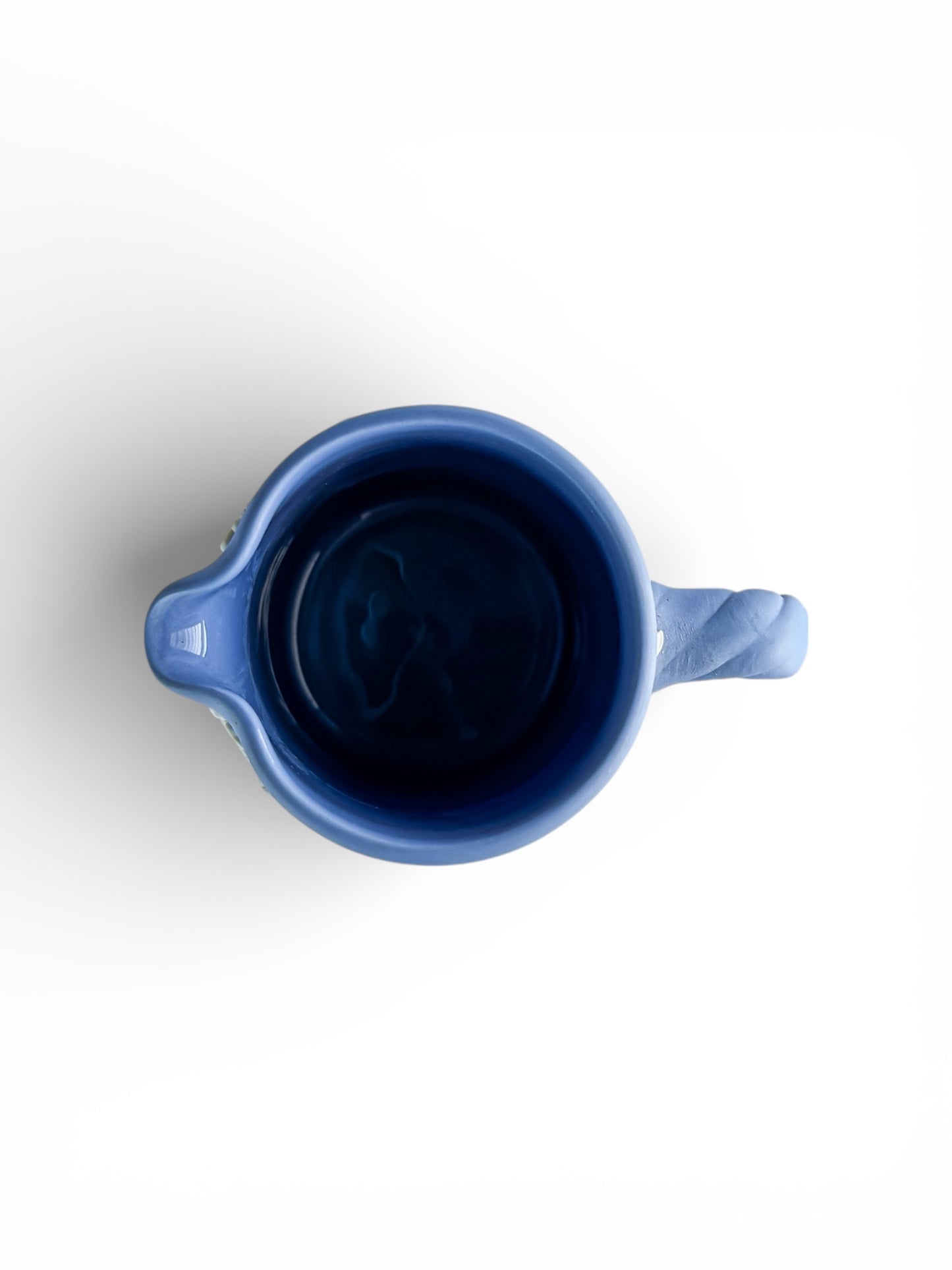 Top view of a blue ceramic pitcher with handle and spout on white background, vintage tableware