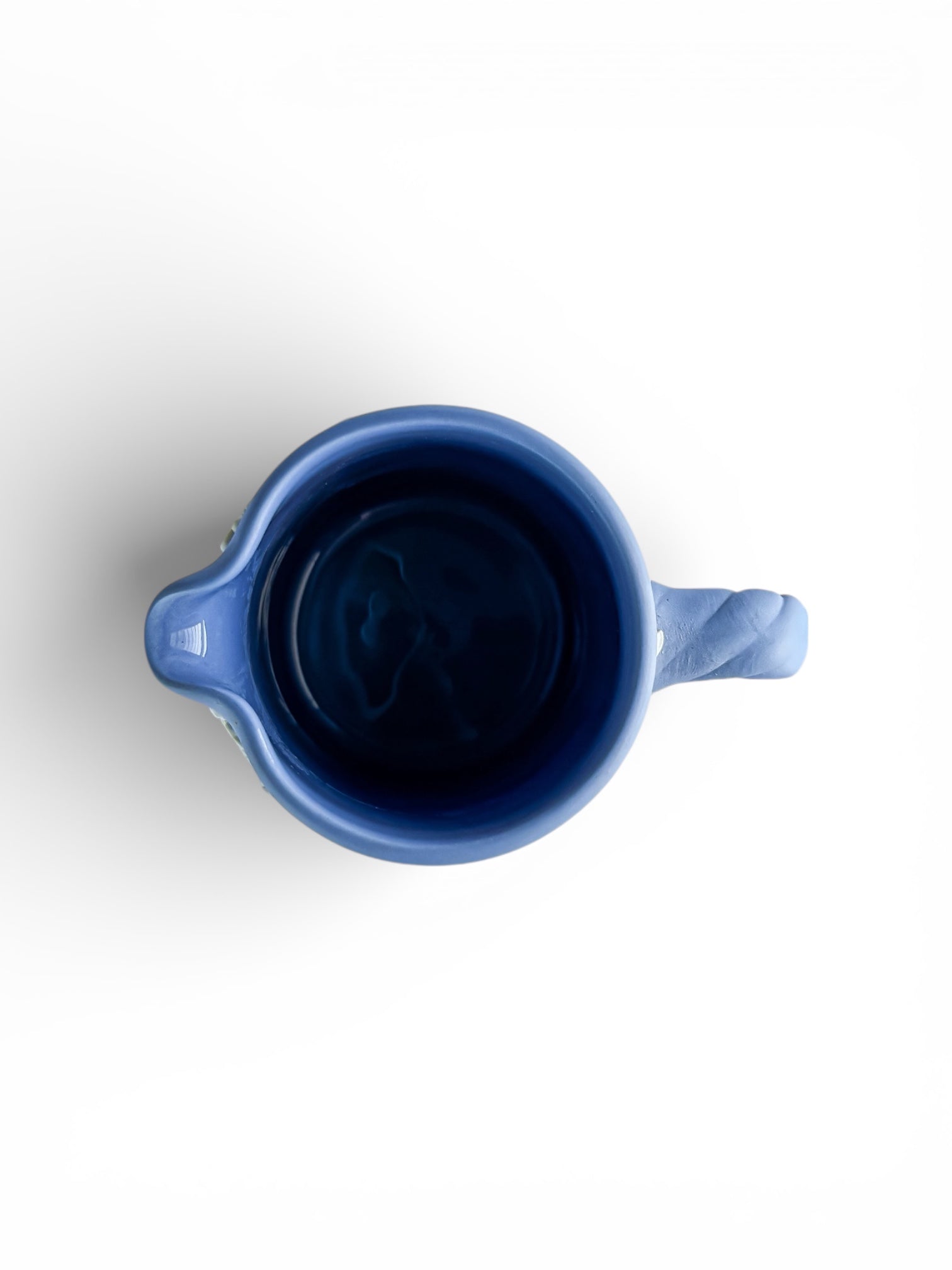 Top view of a blue ceramic pitcher with handle and spout on white background, vintage tableware