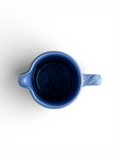 Top view of a blue ceramic pitcher with handle and spout on white background, vintage tableware