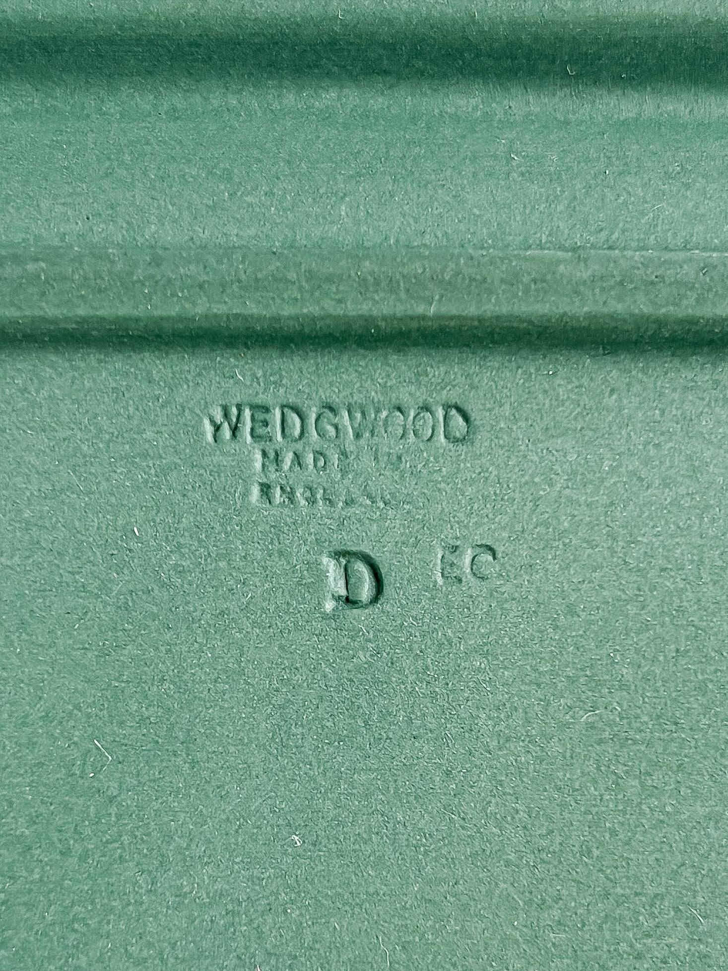 A close-up detail of the impressed backstamp on the green stoneware, clearly reading "WEDGWOOD MADE IN ENGLAND" alongside the letters "D" and "EC".