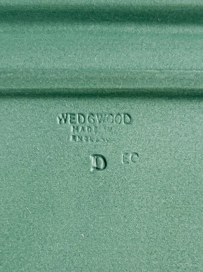 A close-up detail of the impressed backstamp on the green stoneware, clearly reading "WEDGWOOD MADE IN ENGLAND" alongside the letters "D" and "EC".