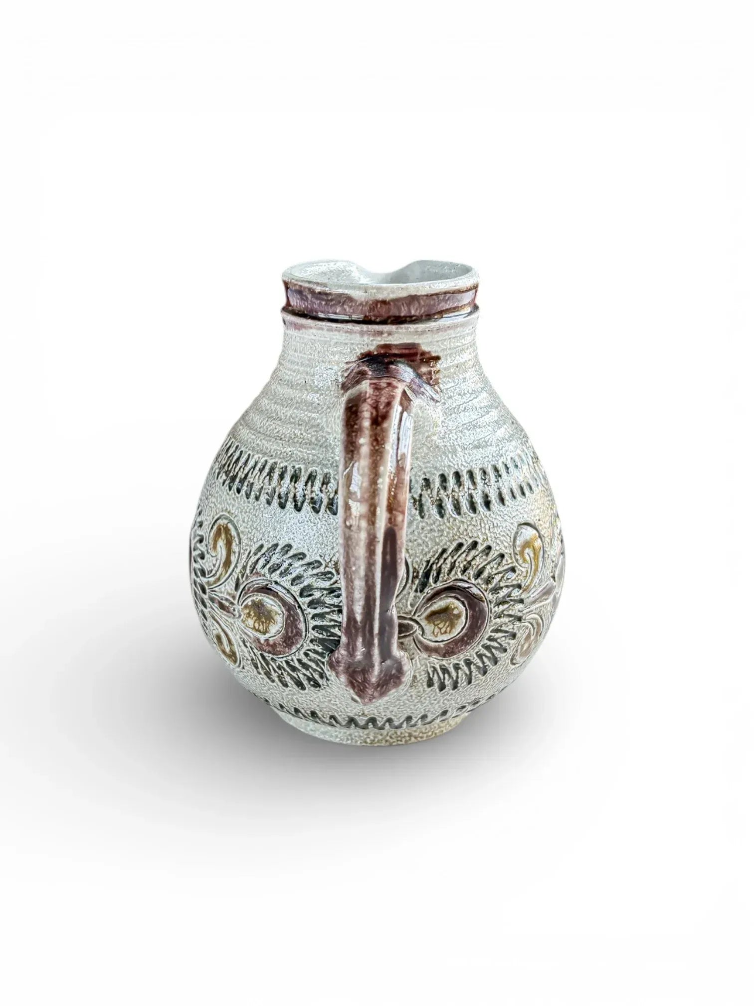 Handcrafted ceramic pitcher with ornate embossed leaf pattern and earthy brown accents