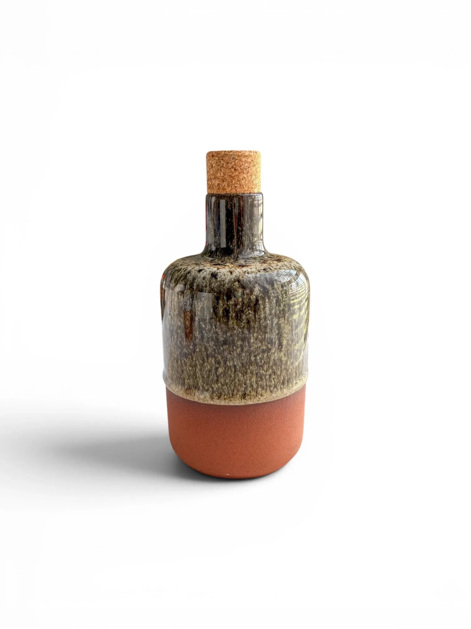 Front view of the Wiid Design olive oil bottle in the brown reactive glaze variant, showing the variegated earthy tones of the glaze and the tactile terracotta bottom.