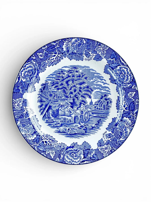 Blue and white vintage ceramic plate with floral border and pastoral countryside scene